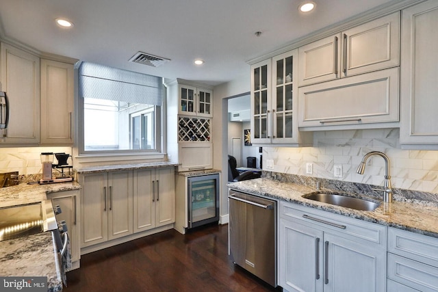 kitchen featuring dishwasher, a sink, glass insert cabinets, and light stone countertops