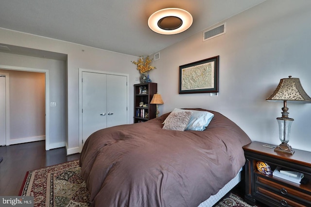 bedroom featuring dark wood-style flooring, a closet, visible vents, and baseboards