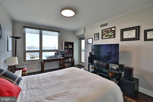 bedroom with baseboards, visible vents, and wood finished floors