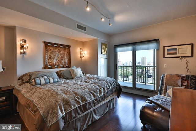 bedroom featuring a city view, dark wood-style flooring, visible vents, and access to exterior