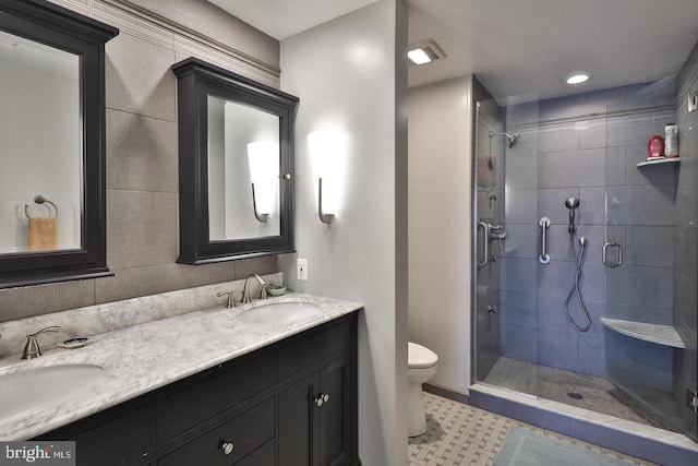 bathroom featuring double vanity, a sink, toilet, and a shower stall