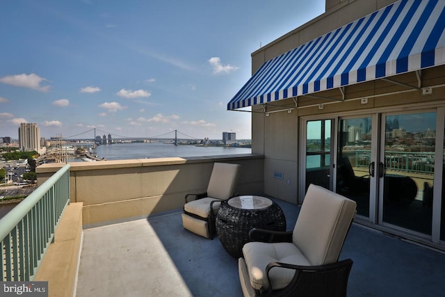 view of patio featuring a water view, a balcony, and a city view