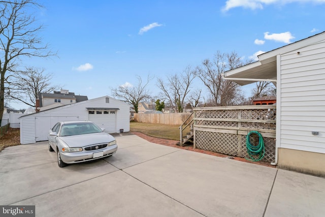 view of property exterior featuring a detached garage, fence, a deck, an outdoor structure, and driveway