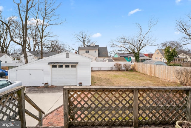 view of yard featuring an outbuilding, a detached garage, fence, and a residential view