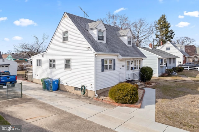 view of side of home with a residential view, fence, and roof with shingles