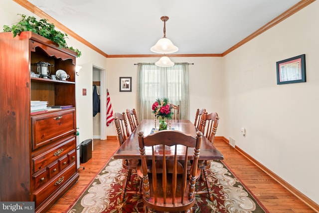 dining room with ornamental molding, light wood-type flooring, and visible vents