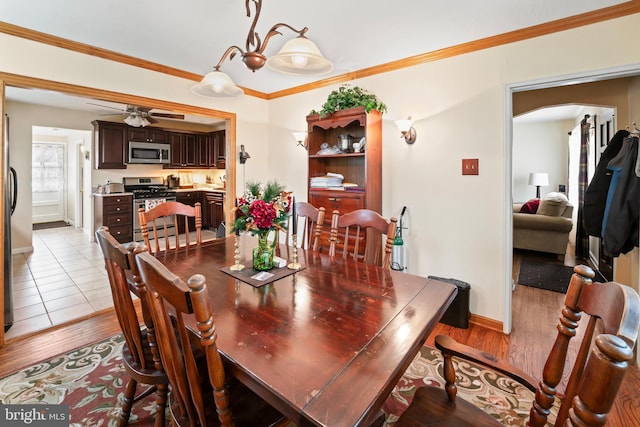 dining space featuring a ceiling fan, ornamental molding, arched walkways, and wood finished floors