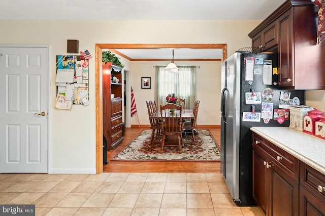 kitchen with light countertops, stainless steel refrigerator with ice dispenser, light tile patterned flooring, and baseboards