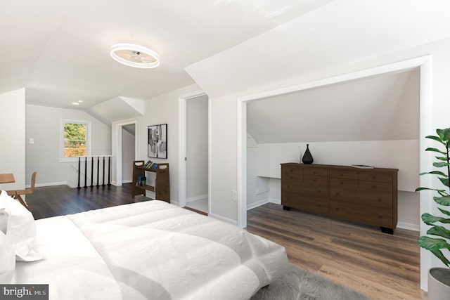 bedroom featuring dark wood-style floors, lofted ceiling, and baseboards