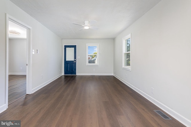 interior space featuring dark wood-style floors, visible vents, baseboards, and a ceiling fan