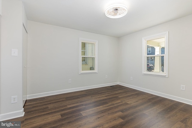 unfurnished room with dark wood-type flooring and baseboards