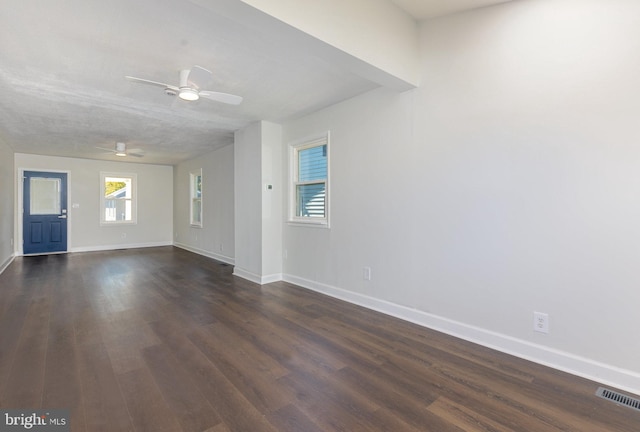 unfurnished living room with visible vents, dark wood finished floors, baseboards, and ceiling fan