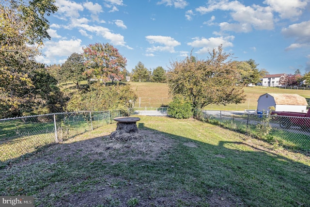 view of yard with a fire pit, a rural view, and a fenced backyard