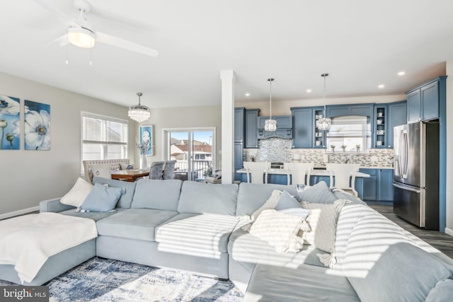 living area featuring ceiling fan with notable chandelier, baseboards, dark wood finished floors, and recessed lighting