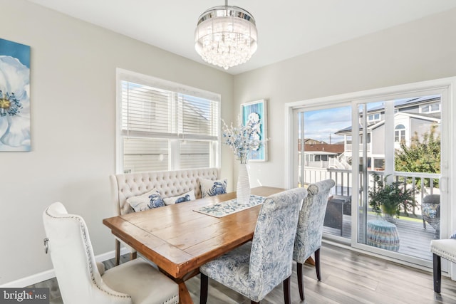 dining room with light wood-style floors, plenty of natural light, baseboards, and an inviting chandelier