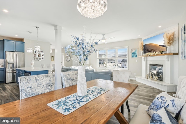 dining area featuring dark wood-type flooring, a glass covered fireplace, a notable chandelier, and recessed lighting