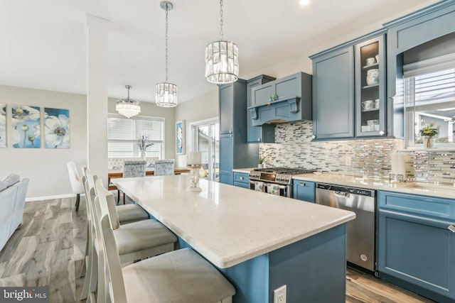 kitchen with a center island, decorative light fixtures, stainless steel appliances, light countertops, and custom range hood