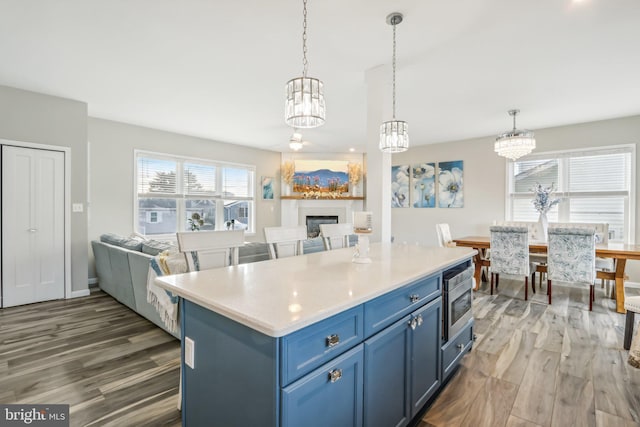 kitchen featuring a fireplace, open floor plan, light countertops, blue cabinetry, and pendant lighting