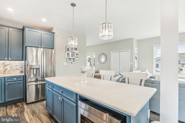 kitchen with decorative backsplash, open floor plan, a center island, stainless steel appliances, and pendant lighting