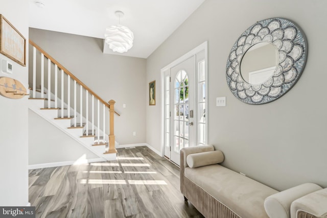 foyer featuring baseboards, stairway, and wood finished floors