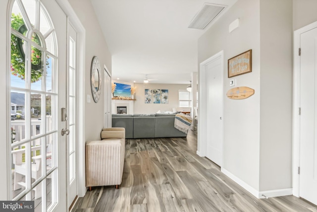 hallway featuring light wood-style floors, visible vents, and baseboards