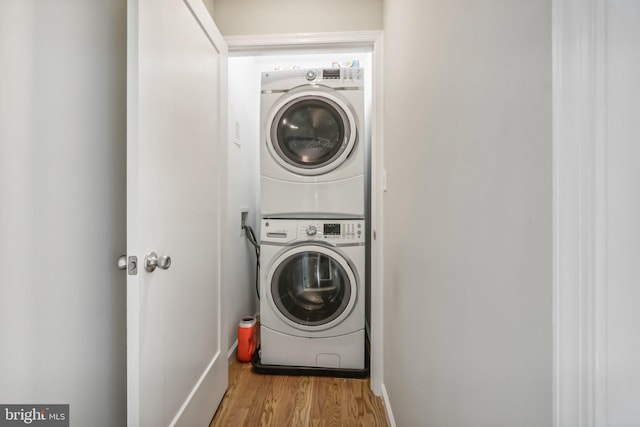 clothes washing area with light wood-style floors and stacked washer / drying machine