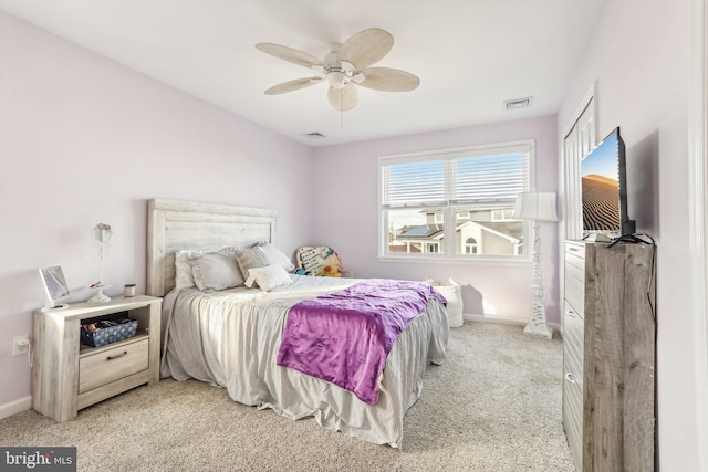 bedroom featuring a ceiling fan, visible vents, light carpet, and baseboards