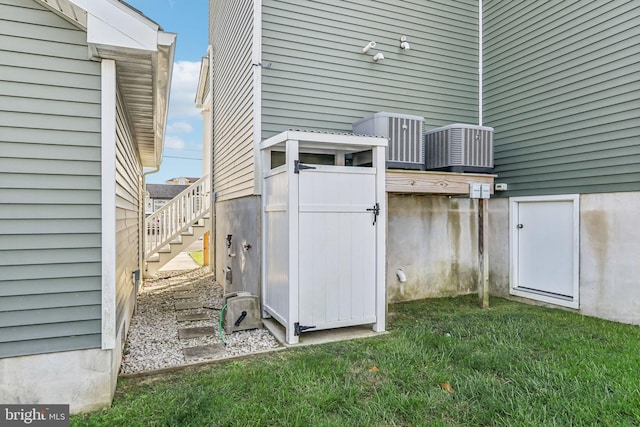 exterior space featuring stairs, central AC unit, and a lawn