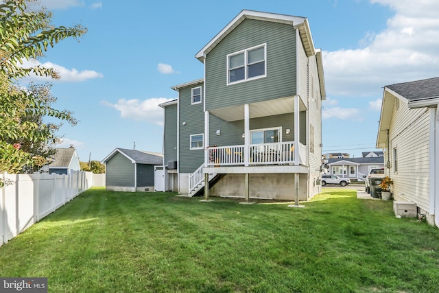 back of house featuring fence, stairway, and a lawn