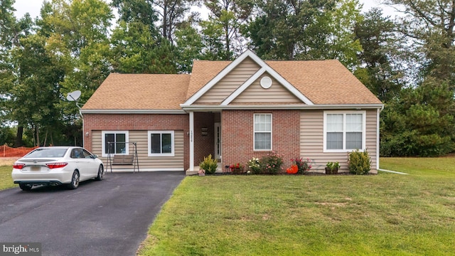 view of front of house featuring roof with shingles, a front yard, aphalt driveway, and brick siding