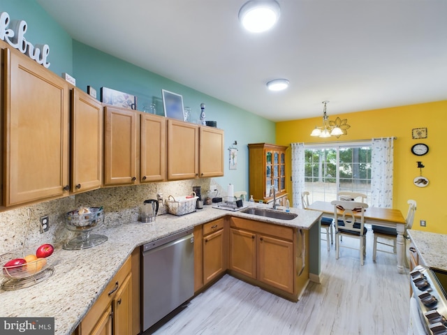 kitchen featuring a peninsula, a sink, appliances with stainless steel finishes, light wood-type flooring, and an inviting chandelier