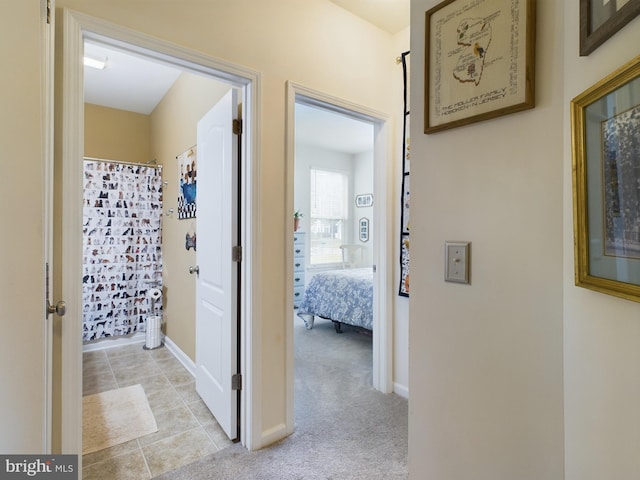 hall featuring baseboards and light colored carpet