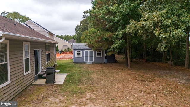 view of yard featuring a storage shed, a patio, and an outbuilding