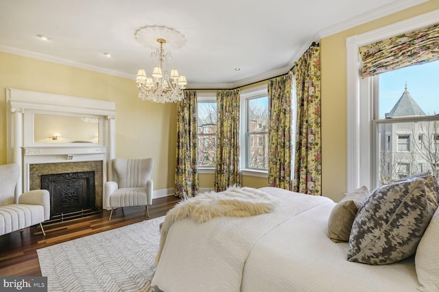 bedroom with a fireplace, baseboards, crown molding, and wood finished floors