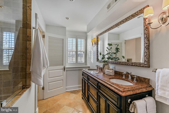 bathroom featuring visible vents, a sink, baseboards, and double vanity