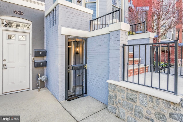 doorway to property featuring a balcony and brick siding