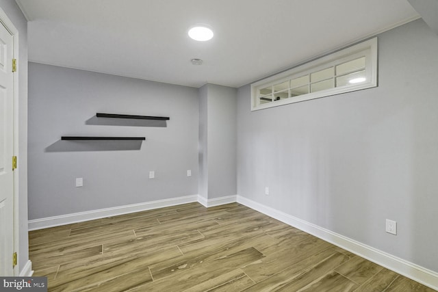 spare room with baseboards and wood finished floors