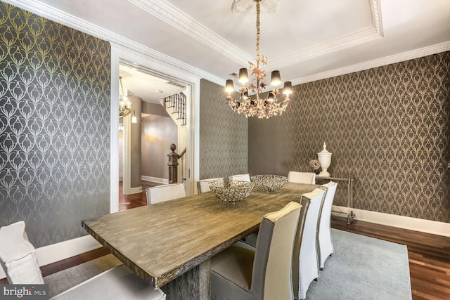 dining room with wallpapered walls, a tray ceiling, wood finished floors, and an inviting chandelier