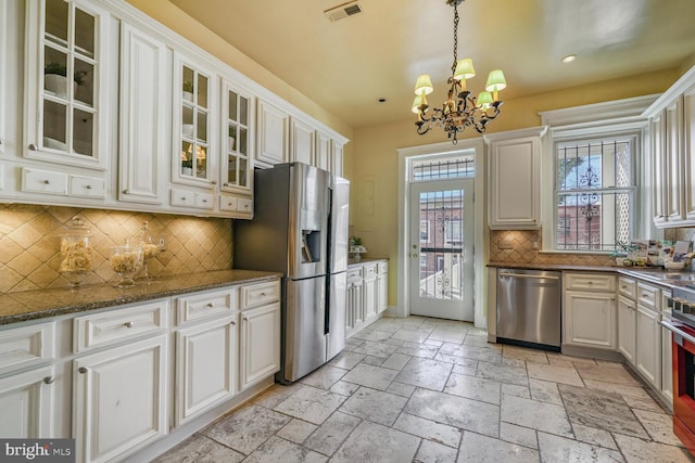 kitchen with decorative light fixtures, stone tile floors, visible vents, appliances with stainless steel finishes, and glass insert cabinets