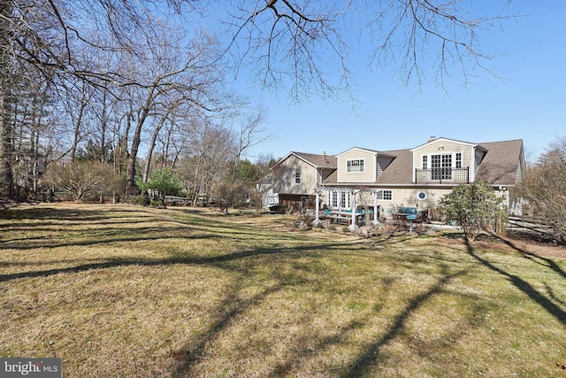 rear view of property with a patio, a yard, roof with shingles, and a chimney