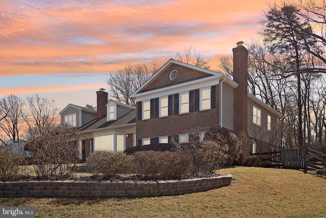 view of front of property featuring a yard, brick siding, and a chimney