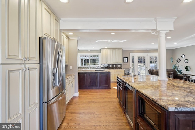 kitchen with stainless steel fridge with ice dispenser, french doors, cream cabinetry, ornate columns, and a sink