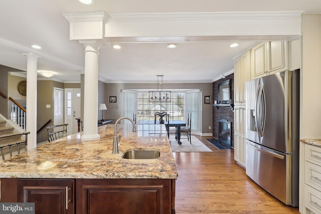 kitchen with stainless steel fridge with ice dispenser, a sink, cream cabinetry, light wood-style floors, and crown molding