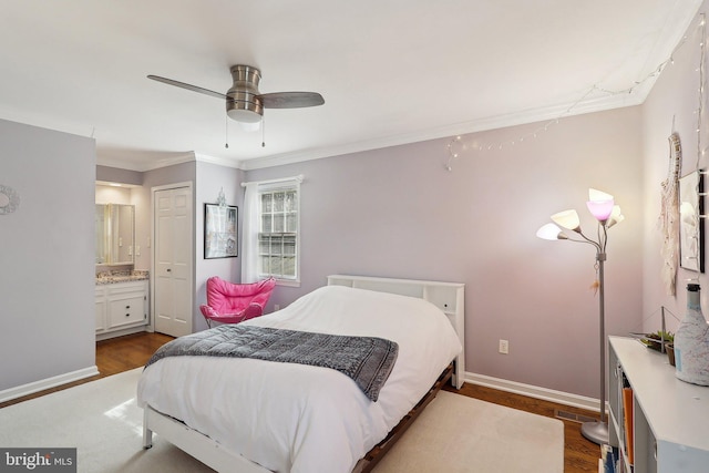 bedroom featuring baseboards, ornamental molding, ensuite bathroom, dark wood-style floors, and a ceiling fan