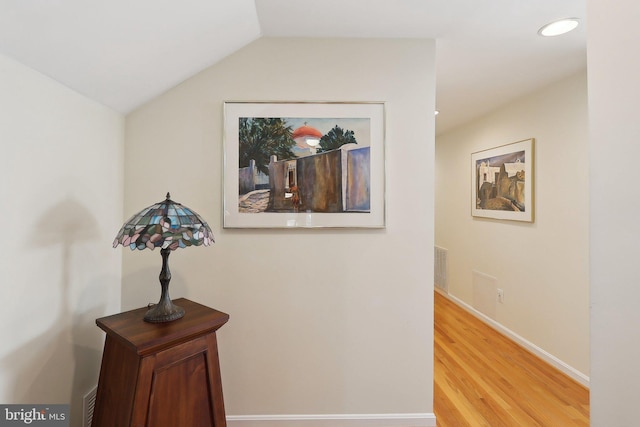 corridor with visible vents, baseboards, lofted ceiling, light wood-style flooring, and recessed lighting