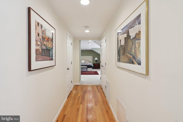 hallway featuring vaulted ceiling, recessed lighting, light wood-style floors, and baseboards