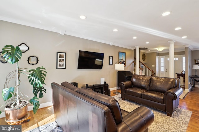 living room with crown molding, wood finished floors, baseboards, and ornate columns