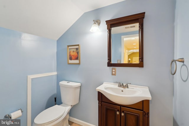 half bathroom with vanity, vaulted ceiling, toilet, and visible vents