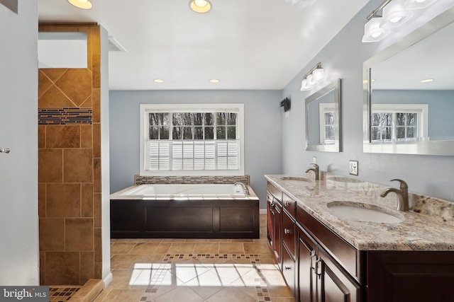 full bath featuring a sink, a garden tub, double vanity, and tile patterned flooring