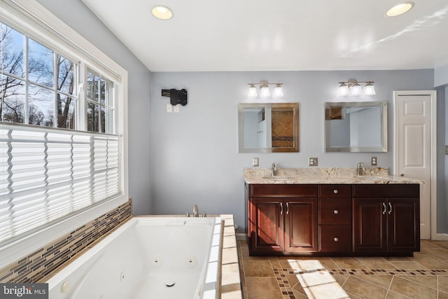 full bath featuring tile patterned flooring, a whirlpool tub, double vanity, and a sink